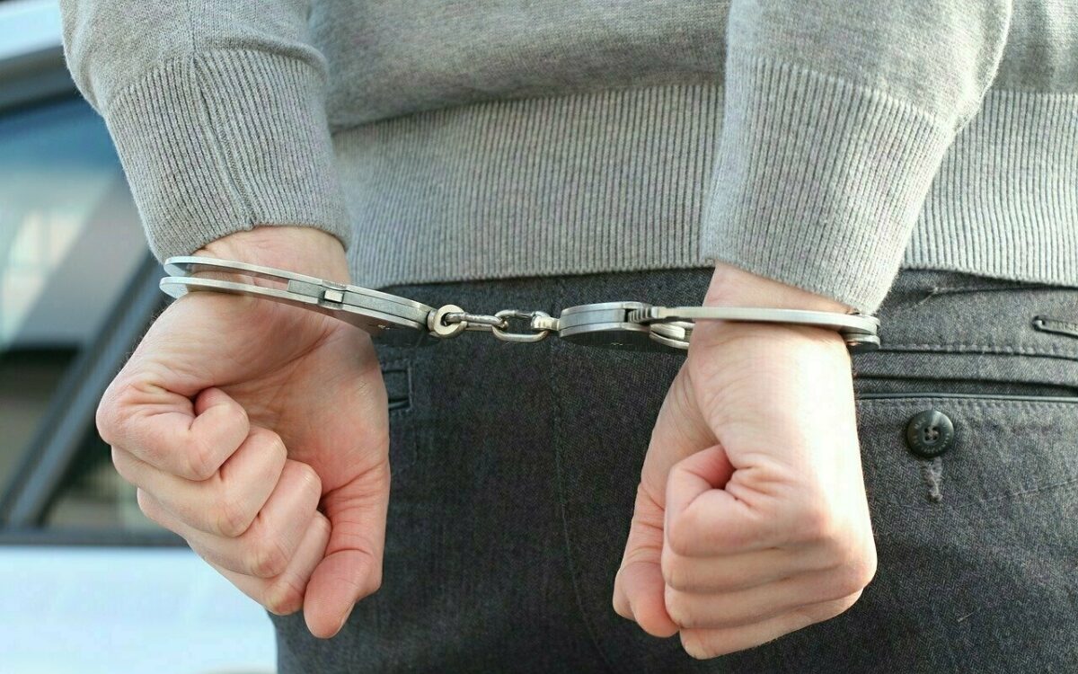 Hände mit Polizei-Handschellen nach einer Festnahme zusammengehalten Hände mit Polizei-Handschellen nach einer Festnahme zusammengehalten